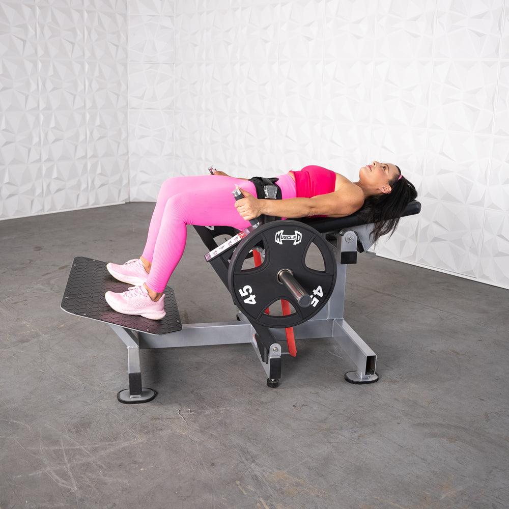 A person using a silver plate loaded hip thruster with branded 45 pound plates loaded