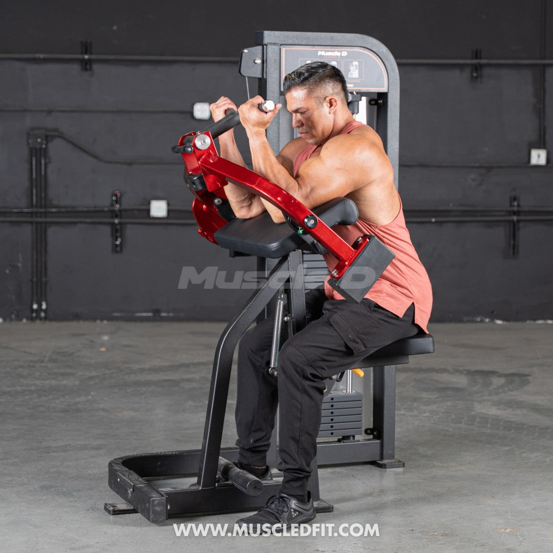 Man exercising on a red and black Classic V2 Biceps Curl machine with 'MuscleFit' branding.