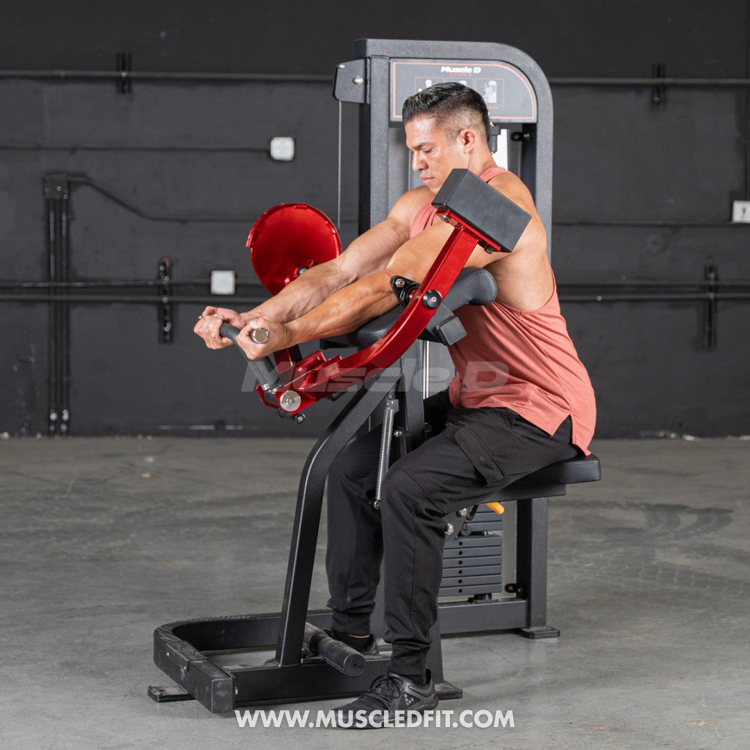 Man exercising on a Classic V2 Biceps Curl machine with a dark background