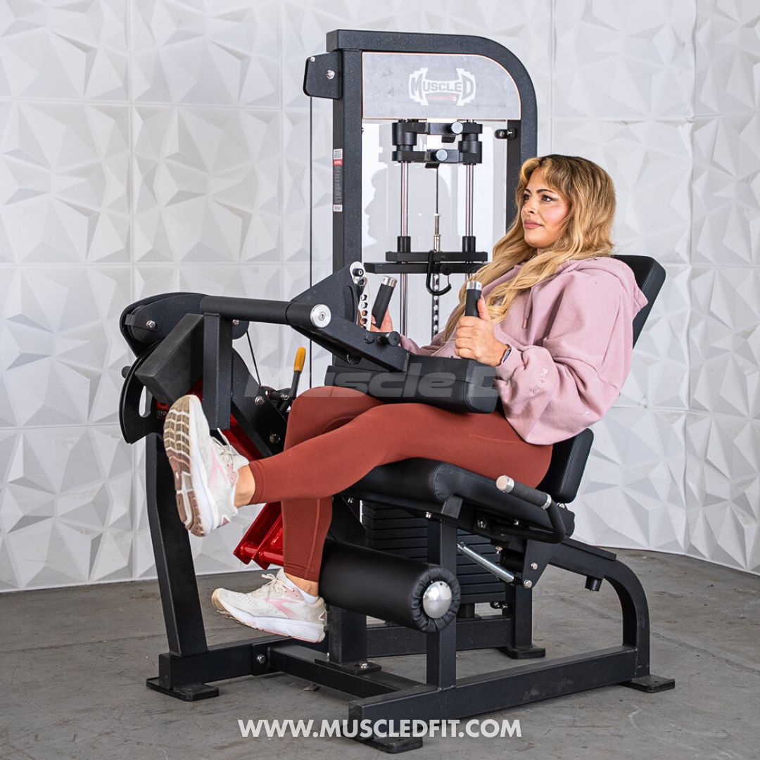 Woman exercising on a Classic V2 Selectorized Leg Extension / Seated Leg Curl Combo machine in a gym setting.