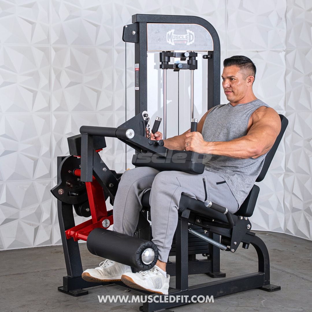 Man exercising on a Classic V2 Selectorized Leg Extension / Seated Leg Curl Combo with a white textured wall background
