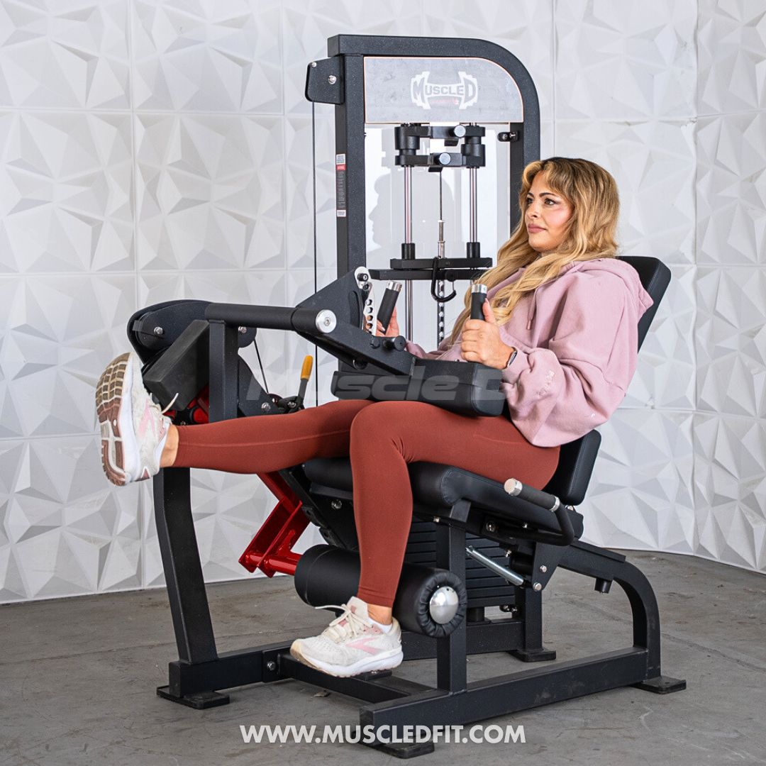 Woman exercising on a Classic V2 Selectorized Leg Extension / Seated Leg Curl Combo machine with a textured wall background