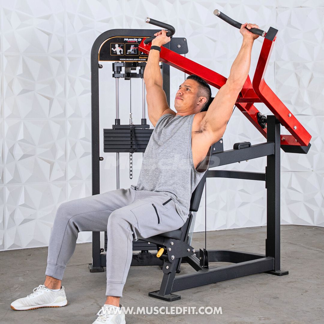 Man exercising on a Classic V2 Shoulder Press press machine in a gym setting