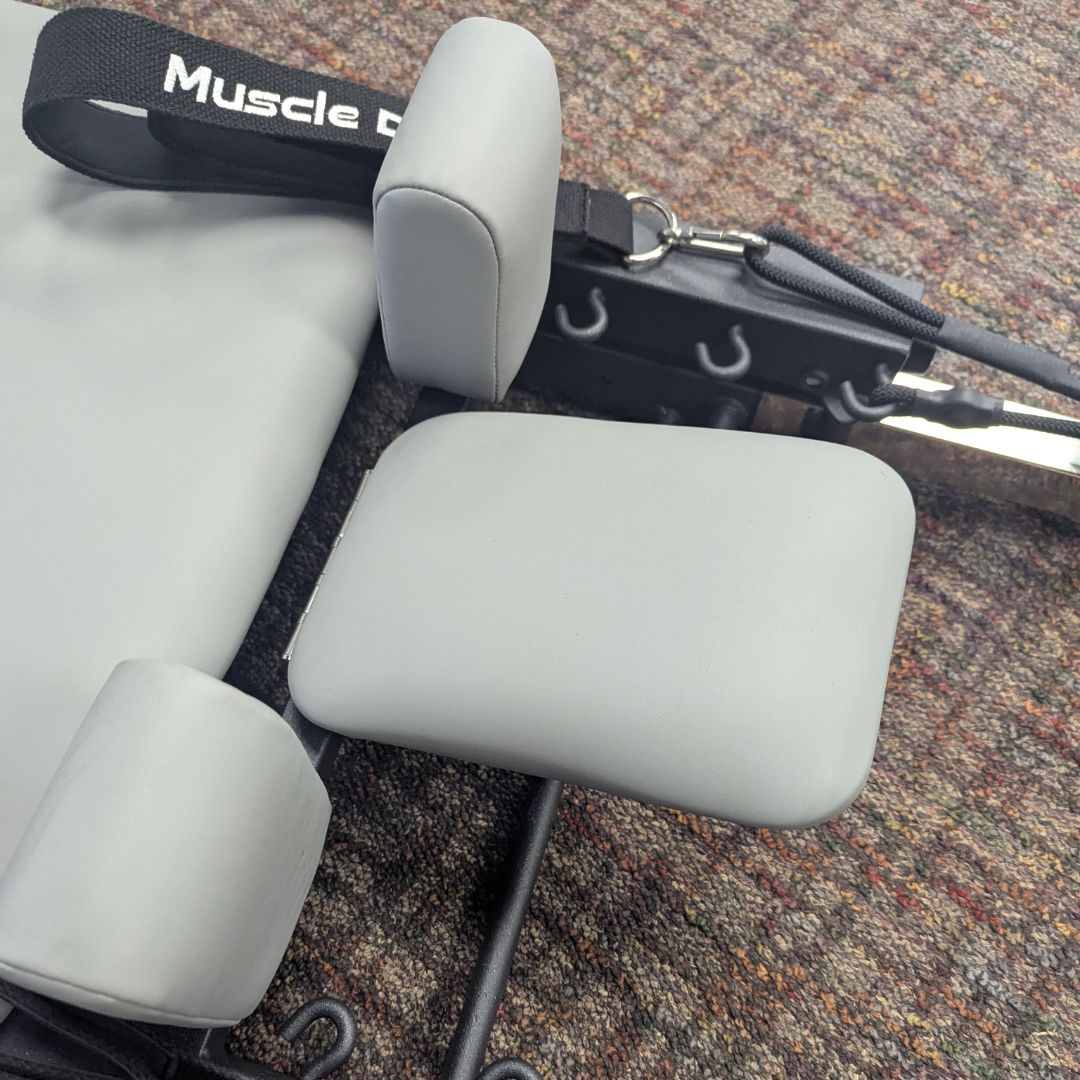 sleek light grey pilates reformer table with padded platform, adjustable foot bar, and sturdy metal frame for home or studio use