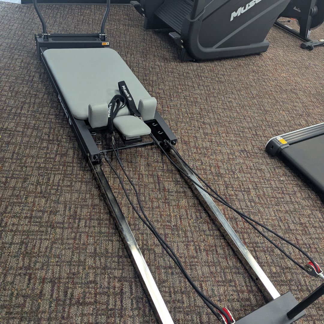 sleek light grey pilates reformer table with padded platform, adjustable foot bar, and sturdy metal frame for home or studio use