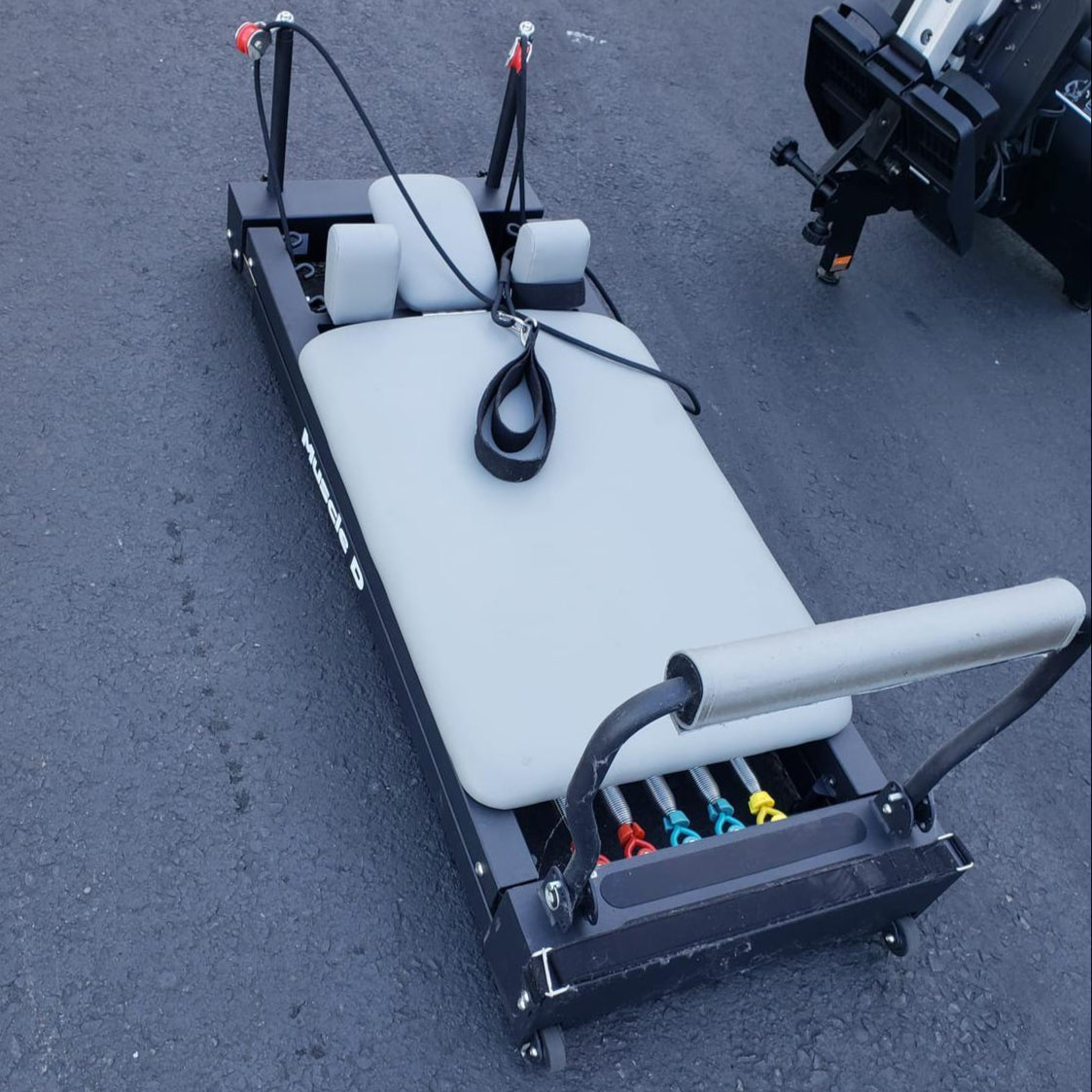 sleek light grey pilates reformer table with padded platform, adjustable foot bar, and sturdy metal frame for home or studio use