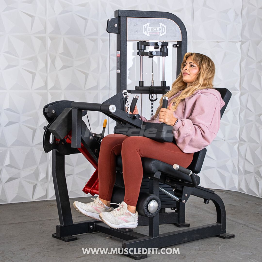 Woman using a Classic V2 Selectorized Leg Extension / Seated Leg Curl Combo with a textured white wall background