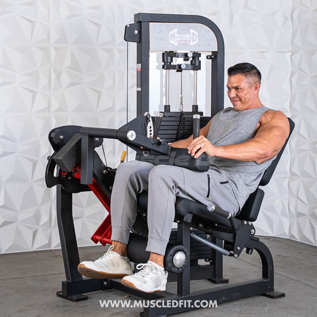 Man using a Classic V2 Selectorized Leg Extension / Seated Leg Curl Combo machine in a gym setting with a textured white wall background.