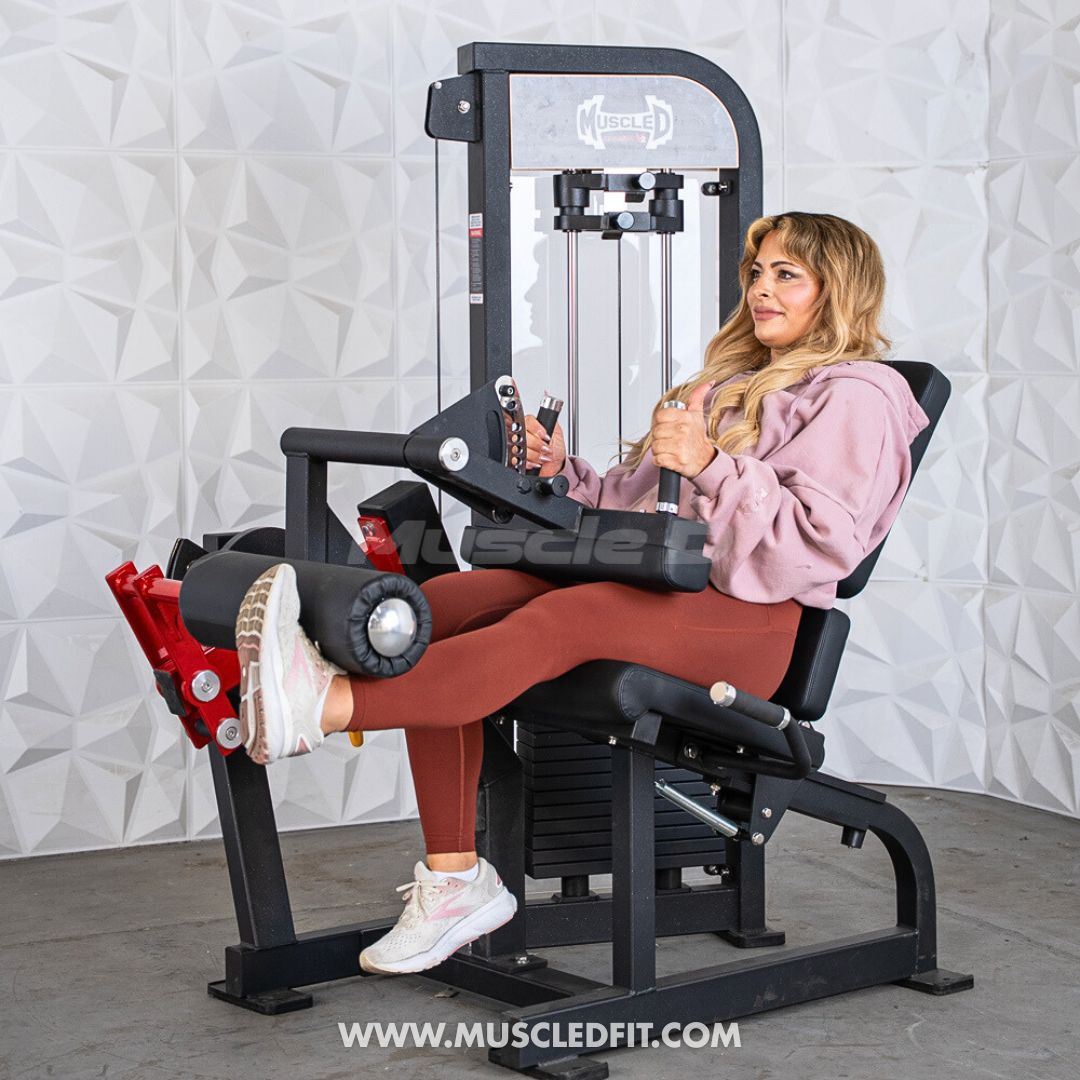 Woman using a Classic V2 Selectorized Leg Extension / Seated Leg Curl Combo machine in a gym setting with a textured wall background