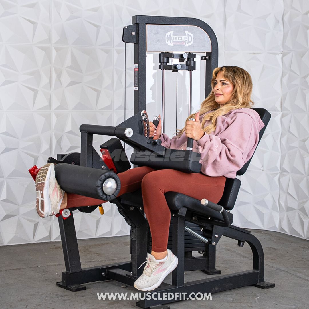 Woman exercising on a Classic V2 Selectorized Leg Extension / Seated Leg Curl Combo machine with a textured white wall background