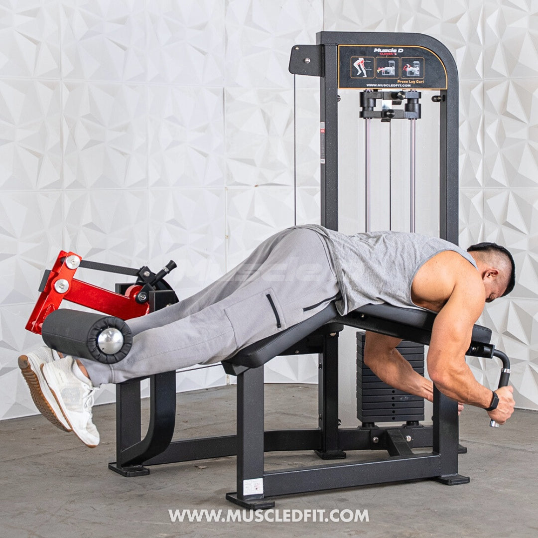 Person using a  Classic V2 Prone Leg Curl machine in a gym setting
