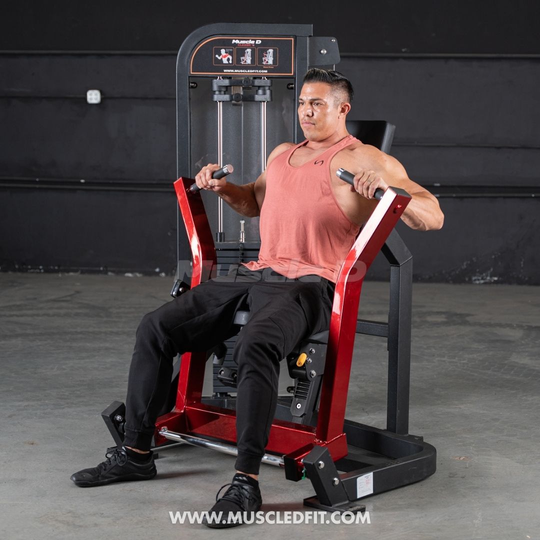 Man exercising on a red and black Classic V2 Selectorized Chest Press machine with a dark background