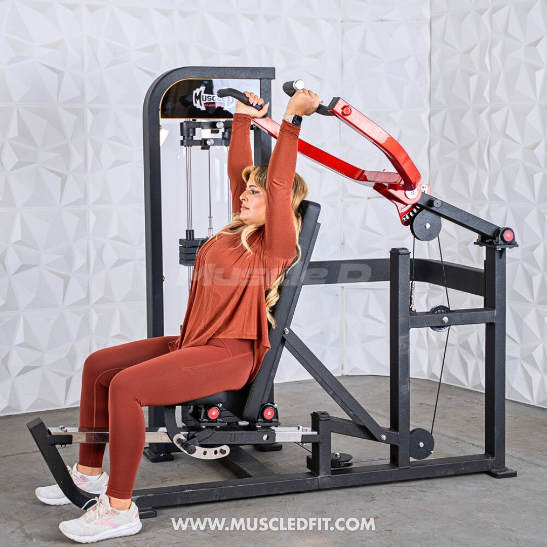 Woman exercising on a Classic V2 Selectorized Multi-Press Chest & Shoulder Press machine with a white textured wall background