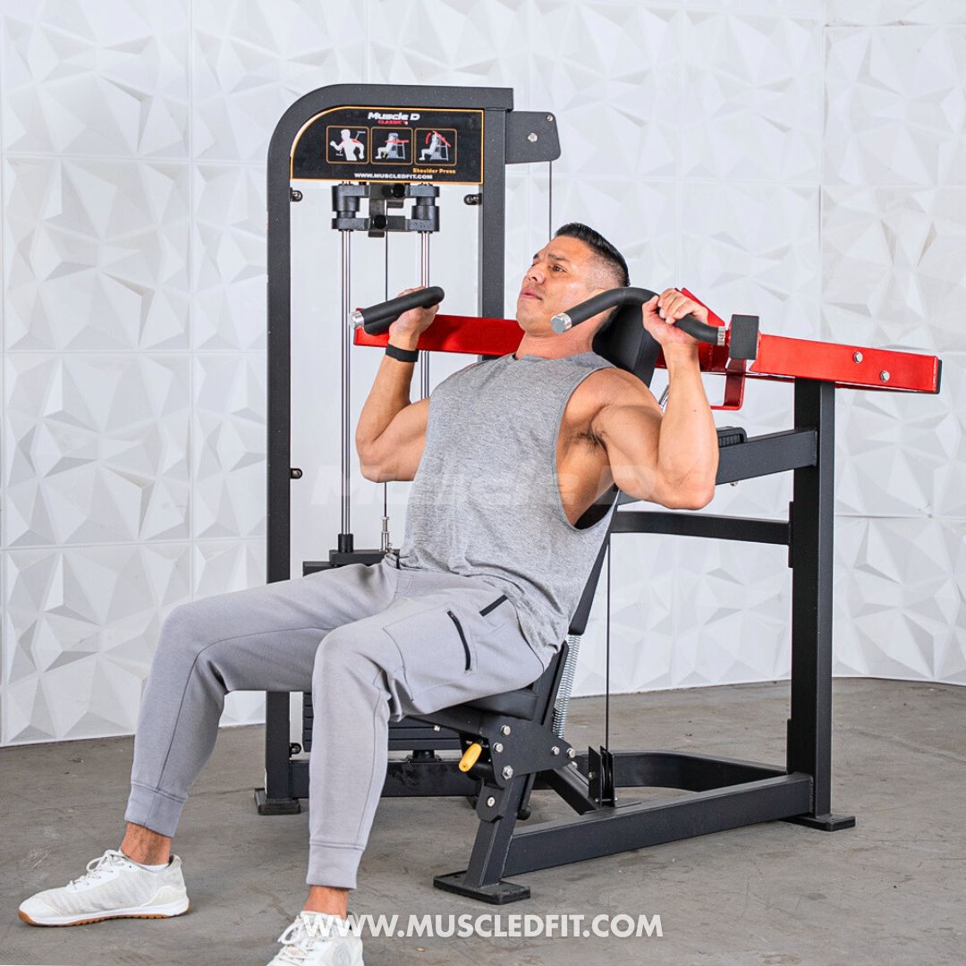 Man exercising on a Classic V2 Shoulder Press machine in a gym setting