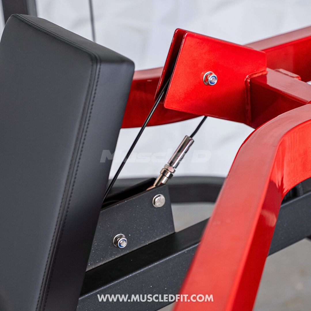 Close-up of a red Classic V2 Shoulder Press  with black padding, featuring the brand 'MuscleD Fit' on a blurred background.