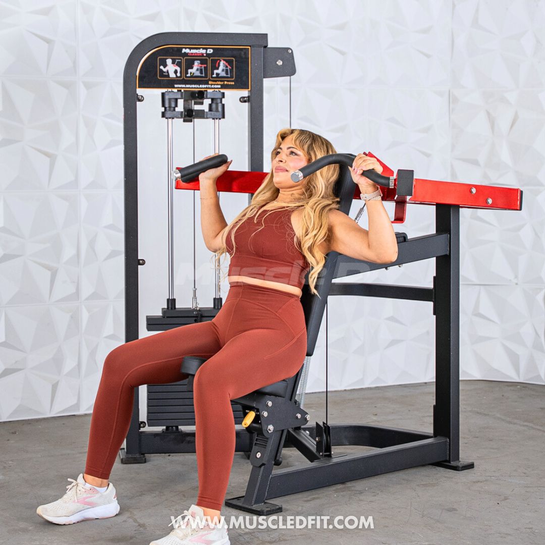Woman exercising on a Classic V2 Shoulder Press machine in a gym setting