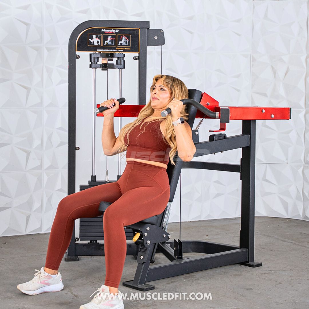 Woman exercising on a Classic V2 Shoulder Press machine in a gym setting