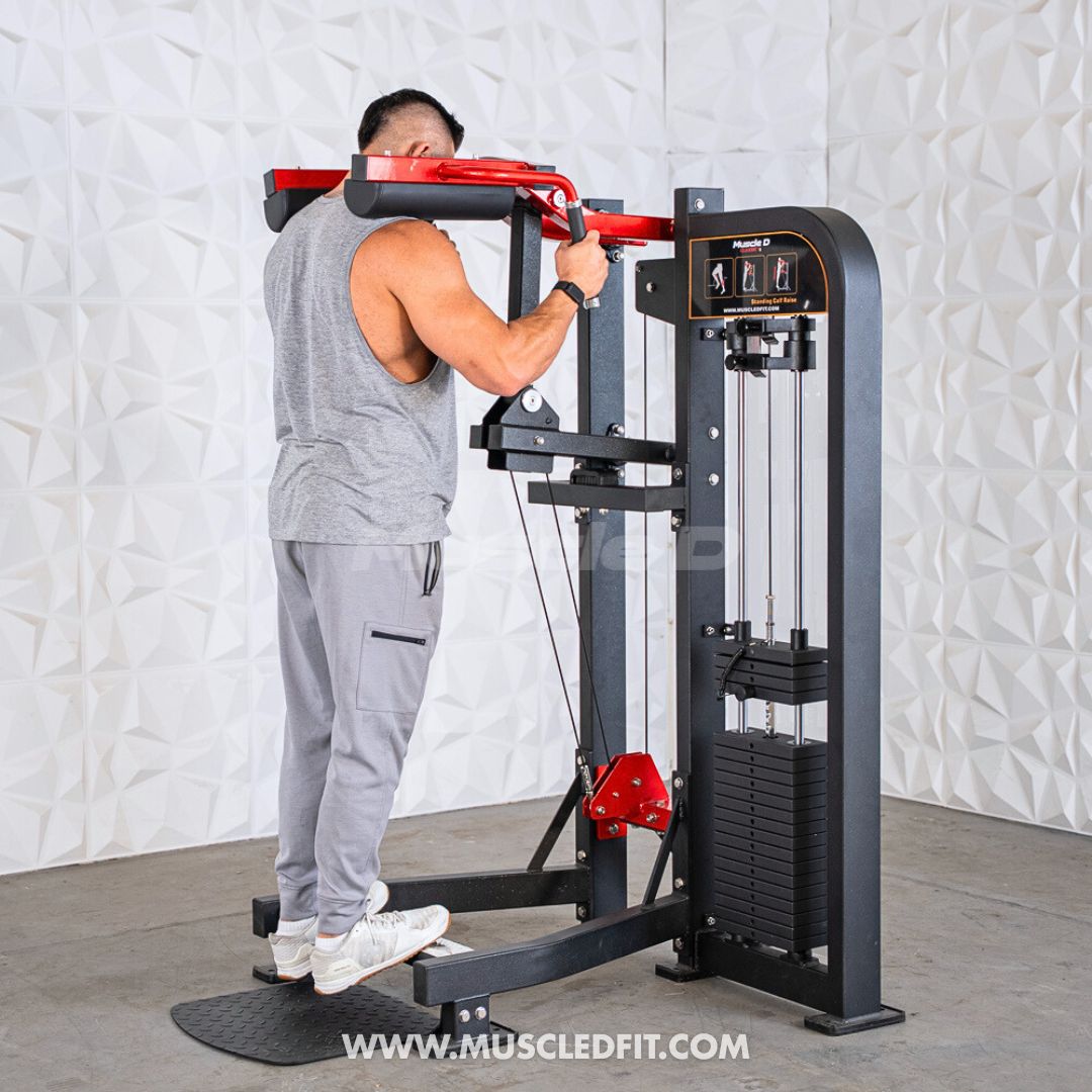 Person using a Classic V2 Selectorized Standing Calf Raise machine in a gym setting with a textured white wall background.