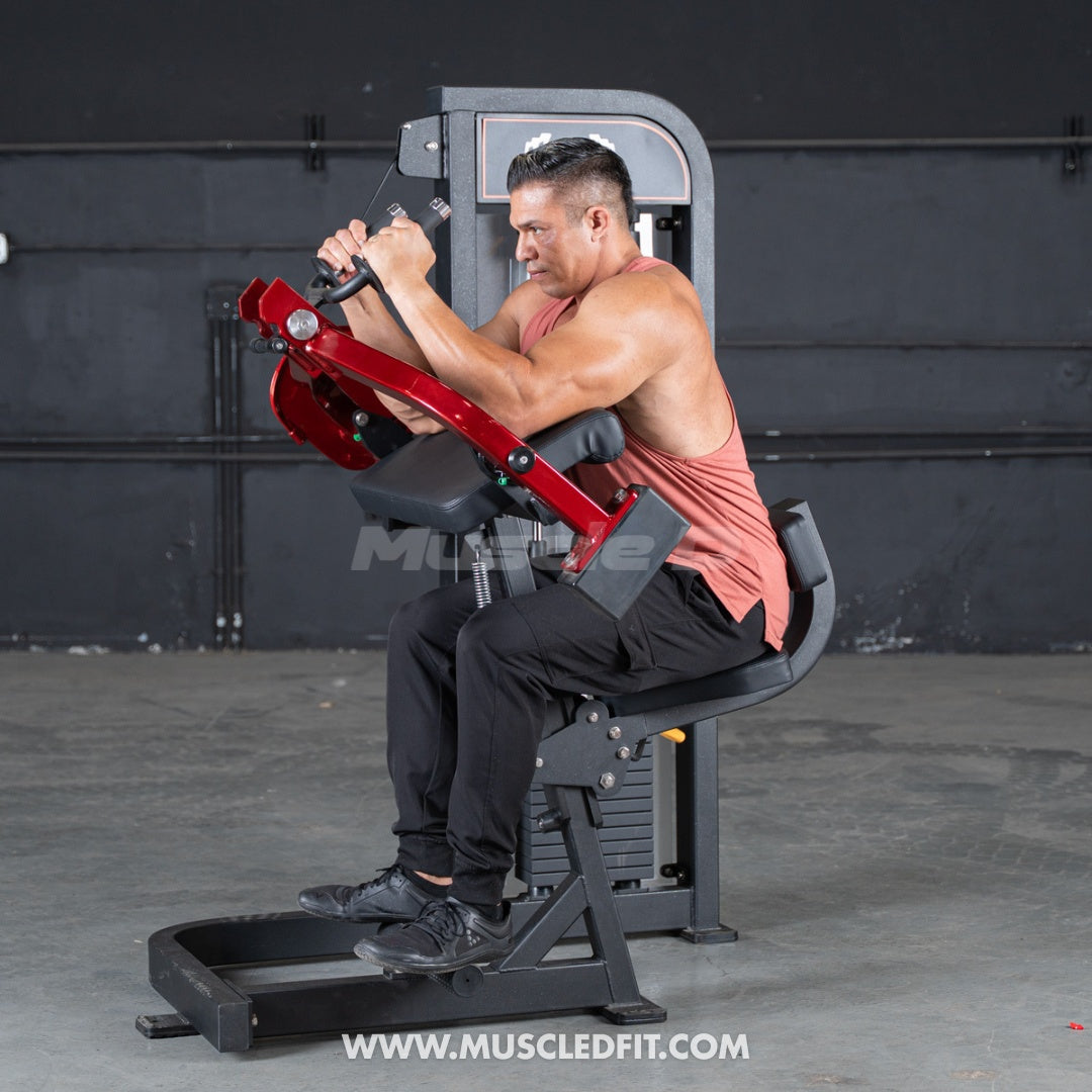 Man exercising on a red and black Classic V2 Triceps extension  machine in a gym setting.