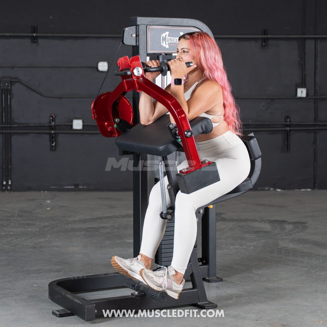 Woman using a red and black  Classic V2 Triceps extension machine in a gym setting with 'Muscleledfit' branding.