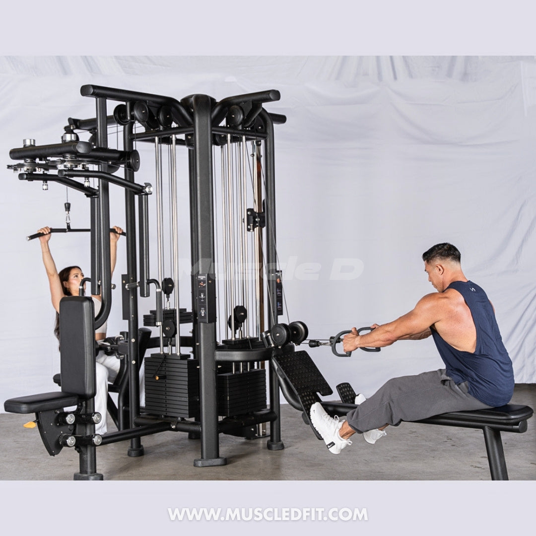 Two people exercising on a 4-Stack Jungle Gym w/ Pec / Rear-Delt machine in a gym setting.